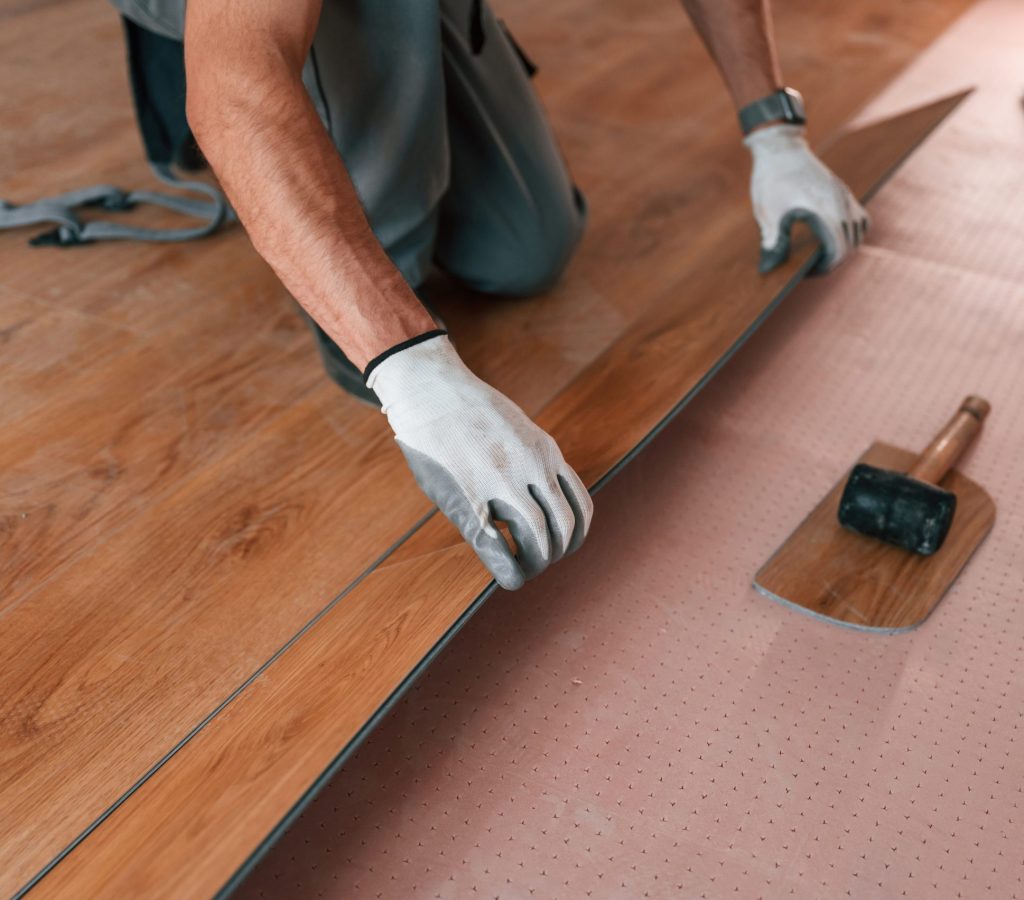 Close up view. Man is installing new laminated wooden floor.